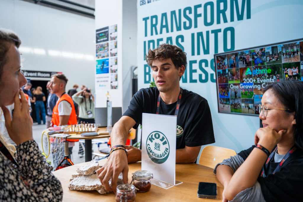 Two founders from a CSE startup at the booth, presenting their product to a visitor.
